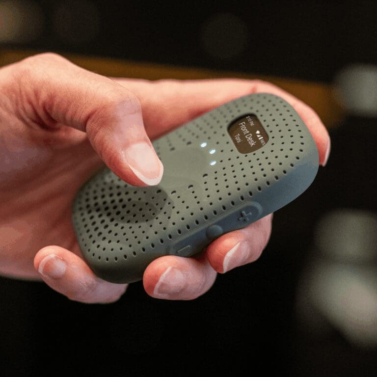 Hand holding RelayM device, showing active communication screen